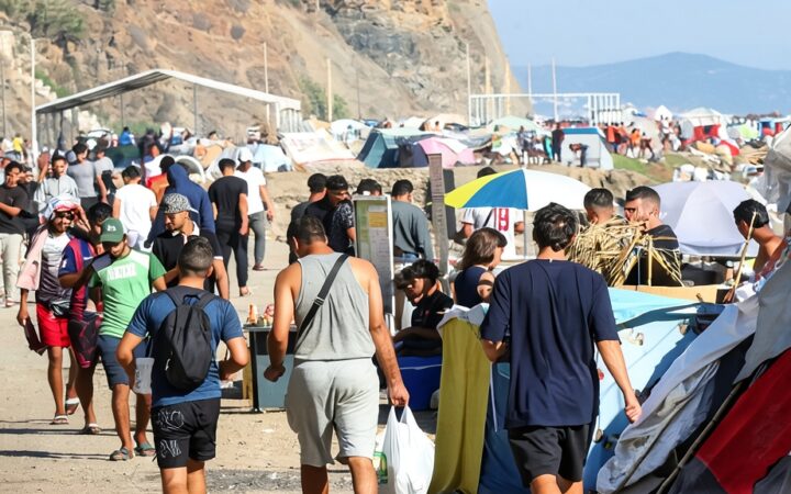 Zona costera e instalaciones provisionales en Ceuta con presencia de vehículos de emergencia.