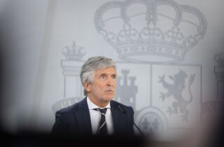 Fernando Grande-Marlaska compareciendo en una rueda de prensa con el escudo de España de fondo